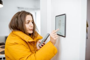 Cold Woman Adjusting Thermostat