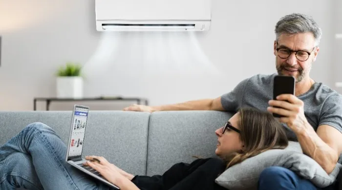 Couple Sitting On Sofa In Living Room With Ductless Ac